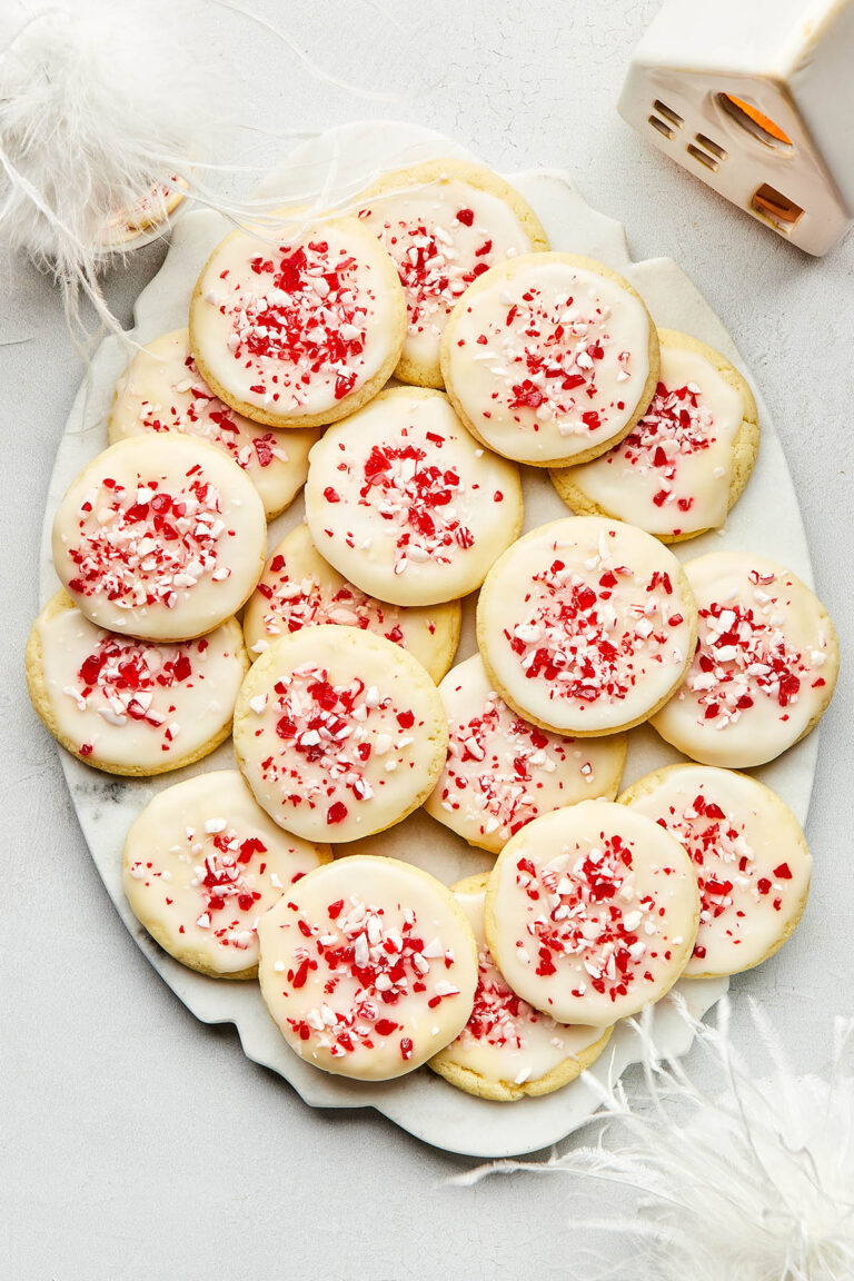 An oval marble platter of peppermint sugar cookies topped with a simple powdered sugar glaze and crushed candy canes.