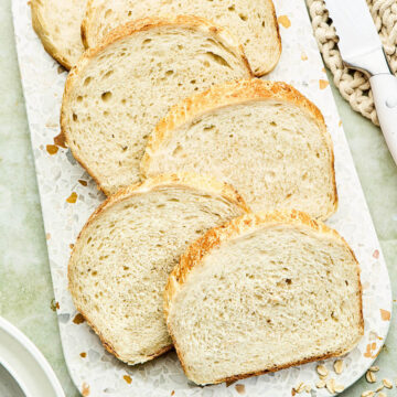 Slices of homemade porridge bread on a speckled board.